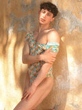 A male model wearing an XDress bodysuit with an orange blossom pattern, posing outdoors in sunlight.