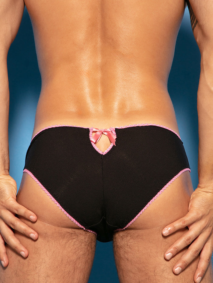 Closeup rear view of a man wearing black ribbed panties with pink lace trim on a blue background.