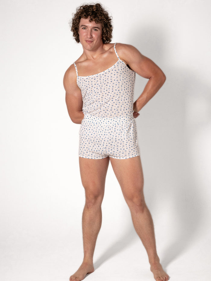 A man wearing a white camisole with a blue floral pattern and matching shorts