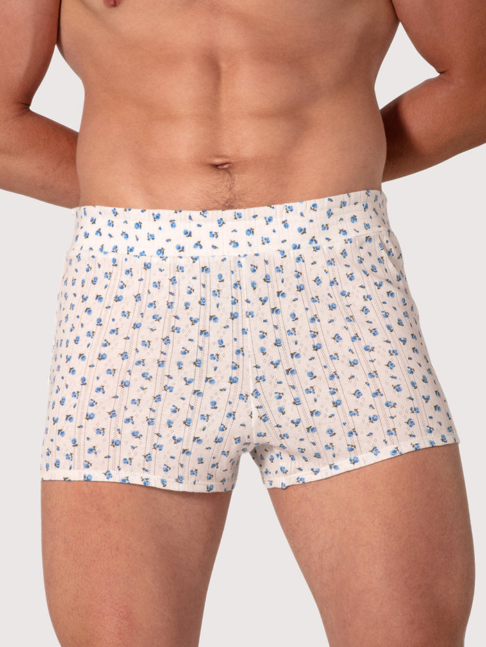 Man wearing white shorts with a blue floral pattern on a plain background