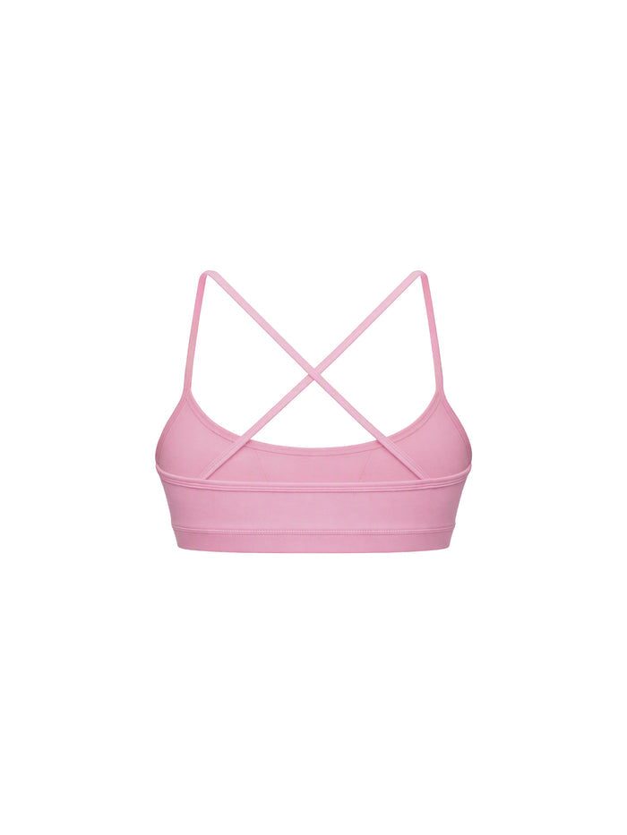 A light pink sports bra with thin crisscrossing shoulder straps, shown from the back on a solid white background.
